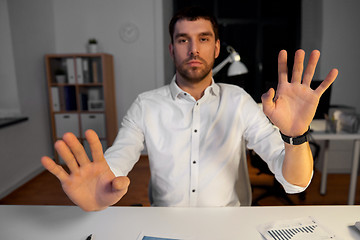 Image showing businessman using gestures at night office