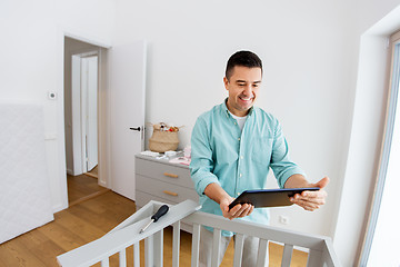 Image showing father with tablet pc assembling baby bed at home