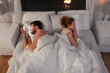 Image showing man using smartphone while girlfriend is sleeping