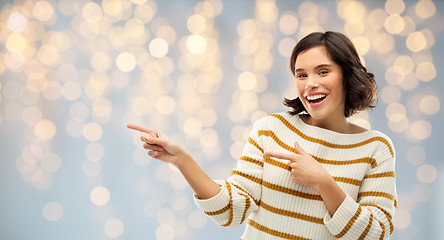 Image showing happy smiling woman pointing fingers to something