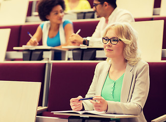 Image showing student girl writing to notebook in lecture hall