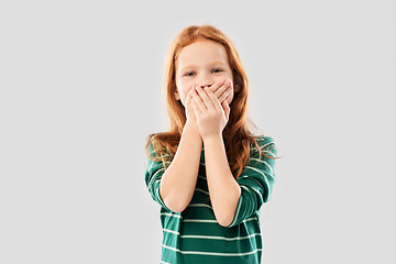 Image showing confused red haired girl covering mouth by hands