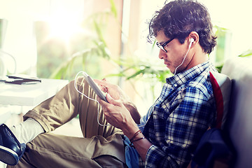 Image showing man with tablet pc and earphones sitting at cafe