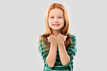 Image showing smiling red haired girl holding something on palms