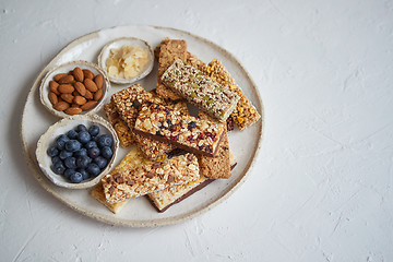 Image showing Mixed composition of energy nutrition bar, granola on ceramic plate over white background