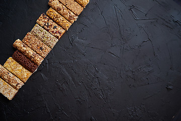 Image showing Various healthy granola bars placed in a row on black stone table