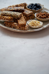 Image showing Mixed composition of energy nutrition bar, granola on ceramic plate over white background