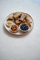 Image showing Mixed composition of energy nutrition bar, granola on ceramic plate over white background