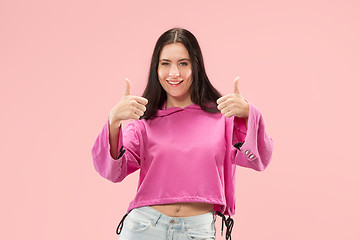 Image showing The happy business woman standing and smiling against pink background.