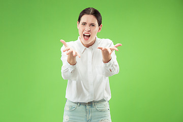 Image showing Beautiful female half-length portrait isolated on green studio backgroud. The young emotional surprised woman