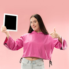 Image showing Portrait of a confident casual girl showing blank screen of laptop isolated over pink background