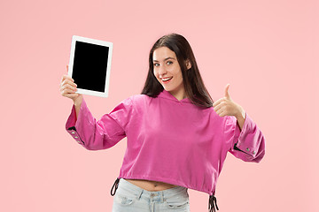 Image showing Portrait of a confident casual girl showing blank screen of laptop isolated over pink background