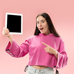 Image showing Portrait of a confident casual girl showing blank screen of laptop isolated over pink background