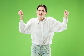 Image showing Beautiful female half-length portrait isolated on green studio backgroud. The young emotional surprised woman
