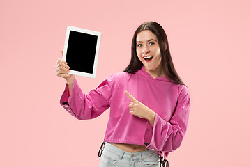 Image showing Portrait of a confident casual girl showing blank screen of laptop isolated over pink background