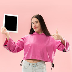 Image showing Portrait of a confident casual girl showing blank screen of laptop isolated over pink background