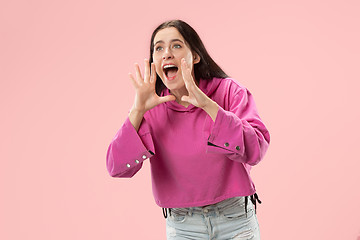 Image showing Isolated on pink young casual woman shouting at studio