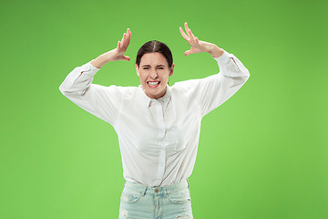 Image showing Beautiful female half-length portrait isolated on green studio backgroud. The young emotional surprised woman