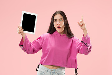 Image showing Portrait of a confident casual girl showing blank screen of laptop isolated over pink background