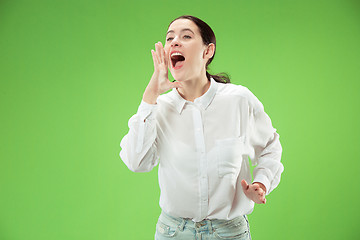 Image showing Isolated on green young casual woman shouting at studio