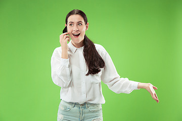 Image showing Young beautiful woman using mobile phone studio on green color background