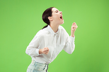 Image showing Isolated on green young casual woman shouting at studio