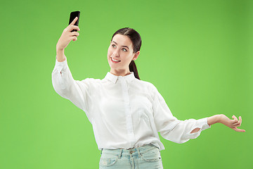 Image showing Portrait of a happy smiling casual girl showing blank screen mobile phone isolated over green background