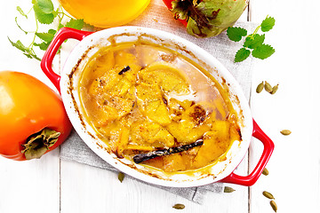 Image showing Persimmons baked with honey in pan on light board top