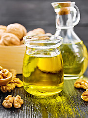 Image showing Oil walnut in jar and decanter on wooden board