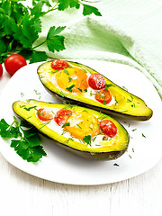 Image showing Scrambled eggs with tomatoes in avocado on light table