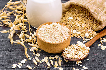 Image showing Flour oat in bowl with oatmeal on dark wooden board