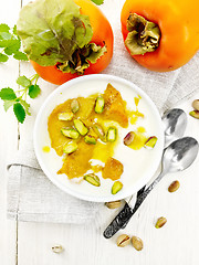 Image showing Dessert of yogurt and persimmon in bowl on board top