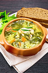 Image showing Soup with couscous and spinach in clay bowl on board