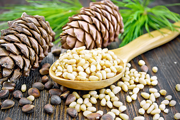 Image showing Cedar nuts peeled in spoon on dark wooden board