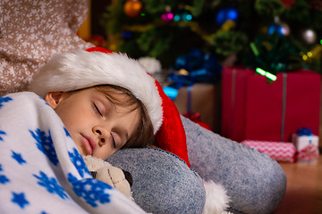 Image showing Girl fell asleep on mom\'s lap on New Year\'s Eve, close-up