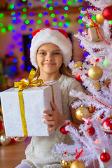 Image showing Beautiful girl with a big New Year\'s gift against the background of blurred lights