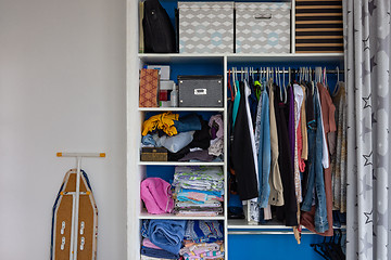 Image showing A cupboard with the usual sloppy man\'s belongings, next to it stands an ironing board