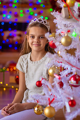 Image showing Beautiful girl sits at the Christmas tree against the background of blurred lights