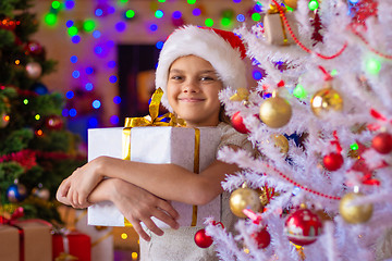 Image showing Happy beautiful girl with a gift at a white Christmas tree