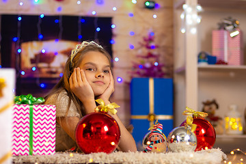 Image showing Girl dreams of a New Year\'s gift, lying on the mat in the New Year\'s interior