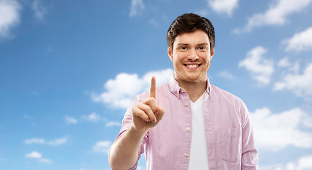 Image showing young man showing one finger over blue sky