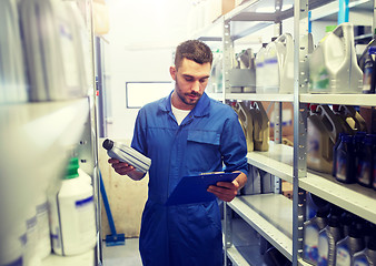 Image showing auto mechanic with oil and clipboard at car shop