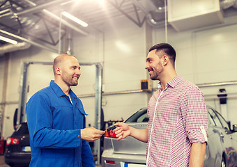 Image showing auto mechanic giving key to man at car shop