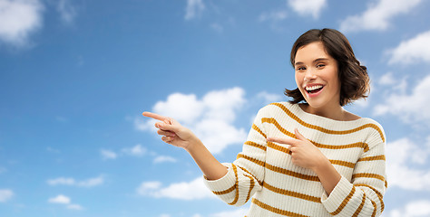 Image showing happy woman pointing fingers to something over sky