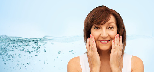 Image showing portrait of smiling senior woman touching her face