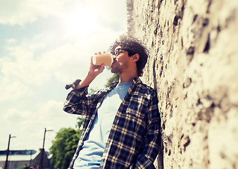 Image showing man in eyeglasses drinking coffee over street wall