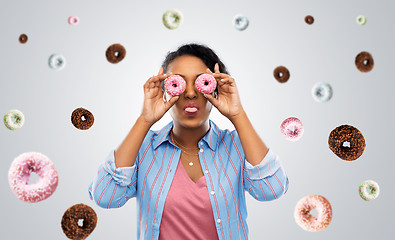 Image showing happy african american woman with eyes of donuts