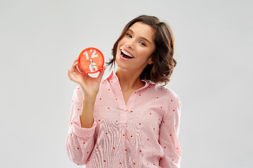 Image showing happy young woman in pajama with alarm clock