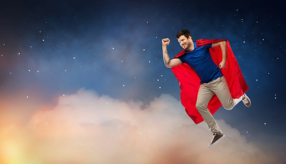 Image showing man in red superhero cape flying over night sky