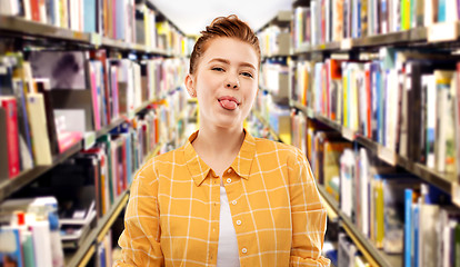 Image showing red haired student girl showing tongue at library